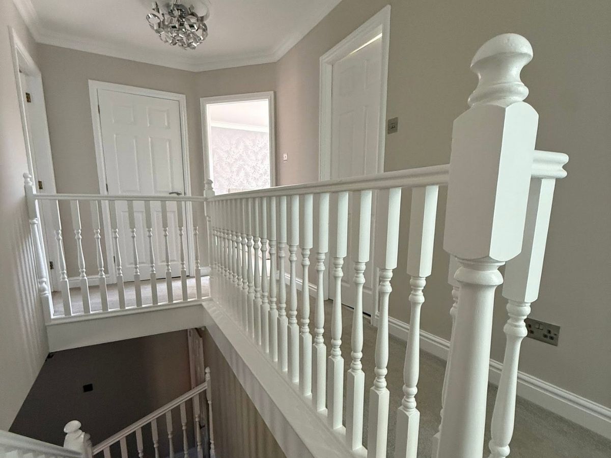 Freshly decorated upstairs landing with neutral painted walls, white woodwork and traditional staircase balustrades.